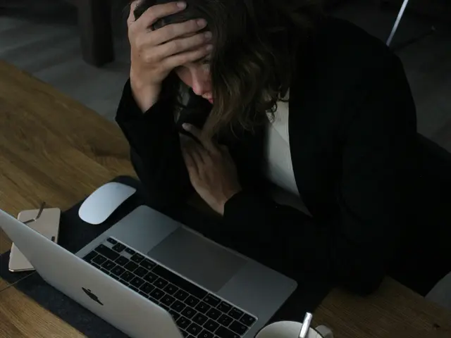 A woman at her laptop with her head in her hand
